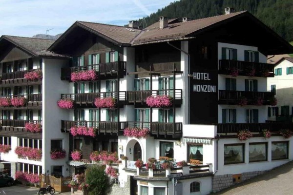 Hotel z drewnianymi balkonami ozdobionymi różowymi kwiatami.