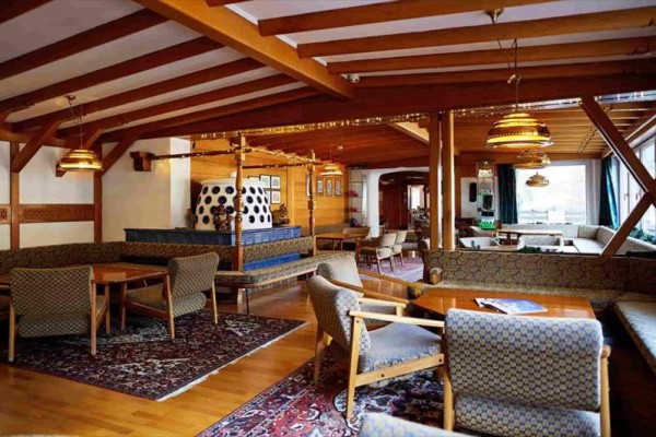 Wnętrze rustykalnej restauracji z drewnianym sufitem i ozdobnym kominkiem.