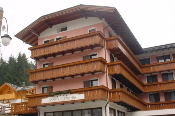 Czteropiętrowy górski hotel z drewnianymi balkonami i różową fasadą.