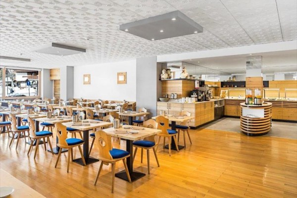 Nowoczesna restauracja z drewnianymi stołami i krzesłami z niebieskim obiciem.