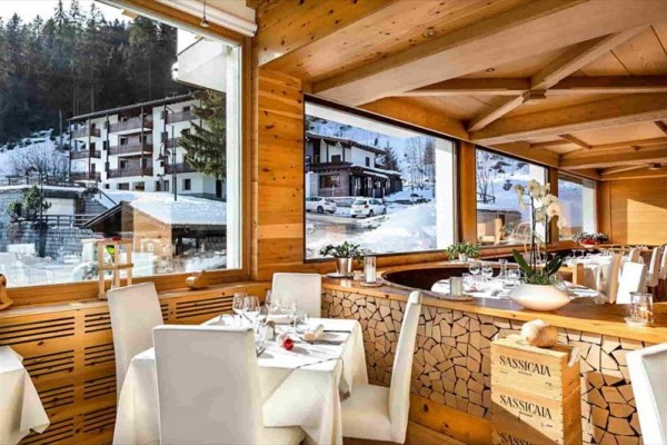 Elegancka restauracja z drewnianym wnętrzem i dużymi oknami z widokiem na ośnieżone góry.