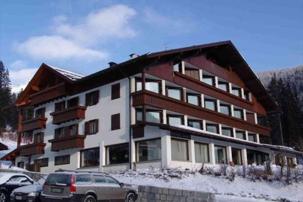 Górski hotel z drewnianymi balkonami i zaśnieżonym dachem.