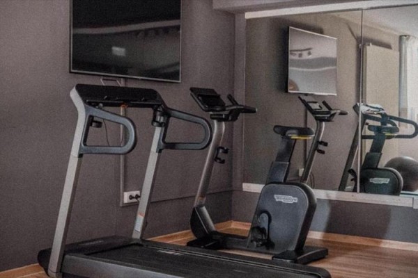 Bieżnia i rower treningowy na siłowni przed lustrem.