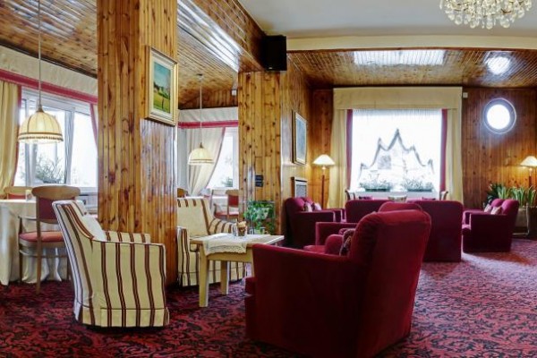 Hotelowa jadalnia z drewnianym wnętrzem i czerwonymi fotelami.