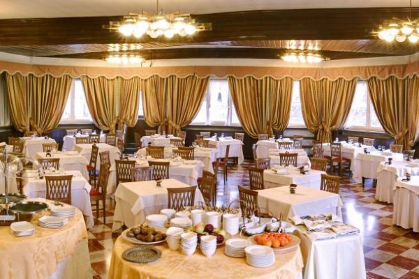 Luksusowa restauracja z okrągłymi stołami i zasłonami wokół okien.