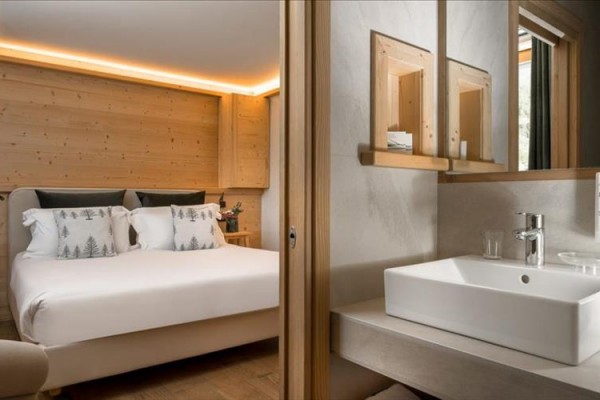 Nowocześnie urządzony pokój hotelowy z łóżkiem małżeńskim i łazienką.