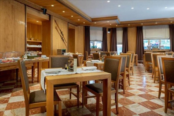 Przestronna restauracja z drewnianymi stołami i brązowymi krzesłami.