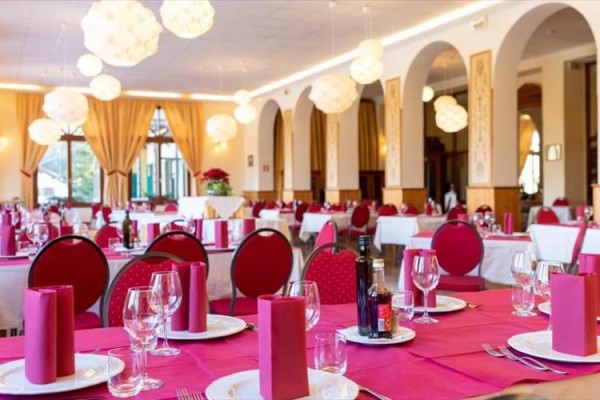 Elegancka restauracja z czerwonymi obrusami i luksusowym oświetleniem.