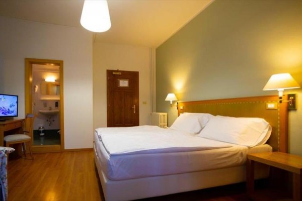 Pokój hotelowy z podwójnym łóżkiem, telewizorem i widokiem na łazienkę.