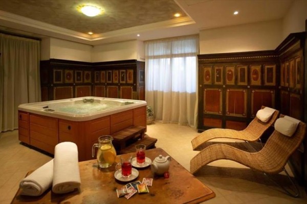 Luksusowy pokój spa z wanną z hydromasażem, leżakami i stołem z napojami.