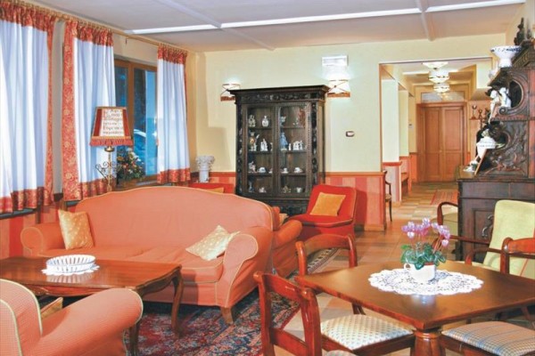 Stylowy salon z czerwonymi kanapami, drewnianymi meblami i szklaną witryną.