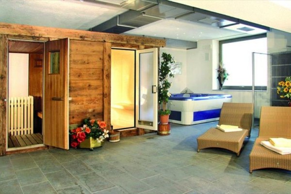 Strefa wellness z drewnianą sauną, jacuzzi i dwoma leżakami.