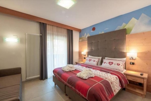Nowocześnie urządzona sypialnia hotelowa z dużym łóżkiem i kolorową pościelą.