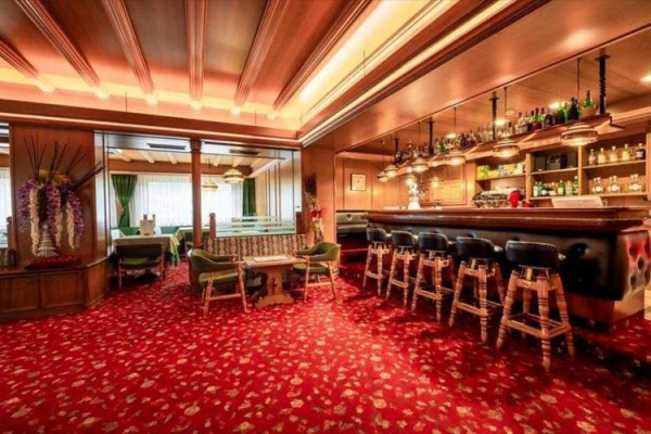 Tradycyjny hotelowy bar z czerwonym dywanem i drewnianymi meblami.