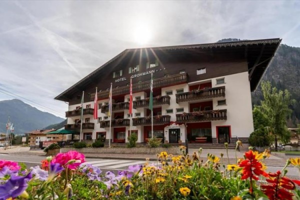 Budynek hotelu z kwiatami na pierwszym planie i górami w tle.