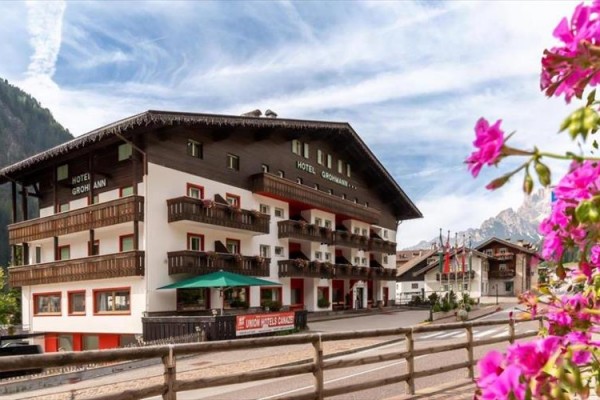 Alpejski hotel z balkonami i kwiatami na pierwszym planie.
