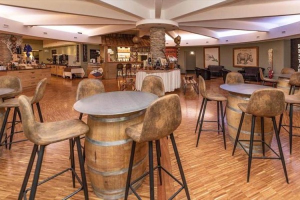 Restauracja z drewnianymi beczkami używanymi jako stoły i krzesłami z wysokim oparciem.