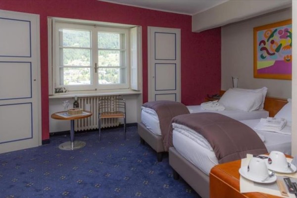 Pokój hotelowy z dwoma osobnymi łóżkami, małym stolikiem i oknem z widokiem.