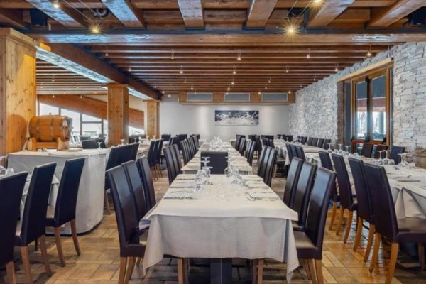 Stylowa restauracja z drewnianymi elementami i nakrytymi stołami.
