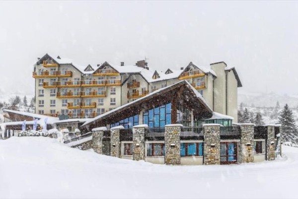 Górski hotel pokryty śniegiem z drewnianymi balkonami.