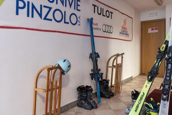 Sprzęt narciarski znajduje się przy ścianie z banerami reklamowymi.