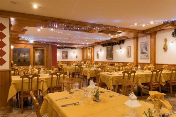 Restauracja z drewnianym wnętrzem i żółtymi obrusami na stołach.
