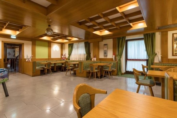 Restauracja z drewnianymi stołami, zielonymi zasłonami i dekoracjami.