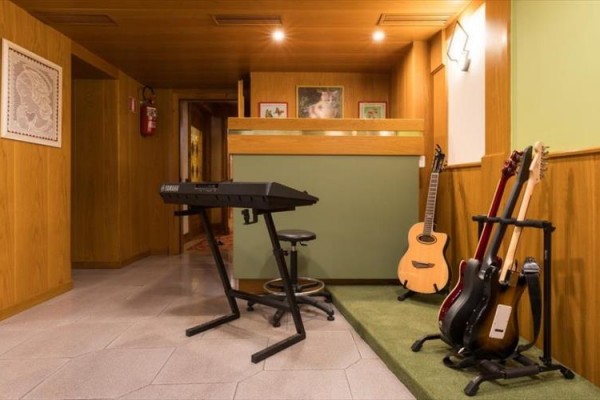 Pokój muzyczny z klawiszami, trzema gitarami i stołkiem.