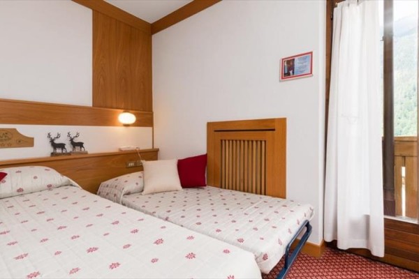 Dwa pojedyncze łóżka w pokoju hotelowym z drewnianą okładziną i widokiem na balkon.