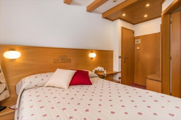 Nowoczesny pokój hotelowy z podwójnym łóżkiem i drewnianą boazerią.