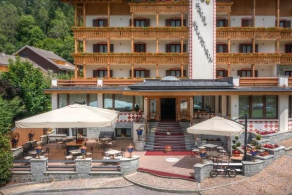 Wejście do górskiego hotelu z tarasem i parasolami.
