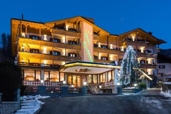 Nocą oświetlony górski hotel z bożonarodzeniowymi dekoracjami.