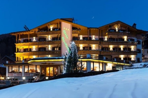 Hotel z jasnym drewnianym wykończeniem i oświetleniem w zaśnieżonym krajobrazie o zmierzchu.