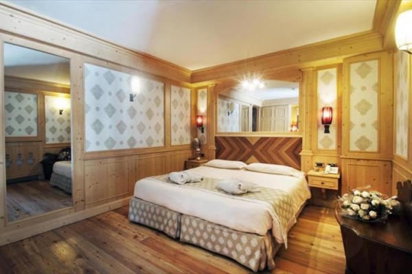 Elegancki pokój hotelowy z łóżkiem małżeńskim i drewnianą boazerią.