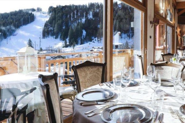 Restauracja z widokiem na ośnieżone góry i stok narciarski.