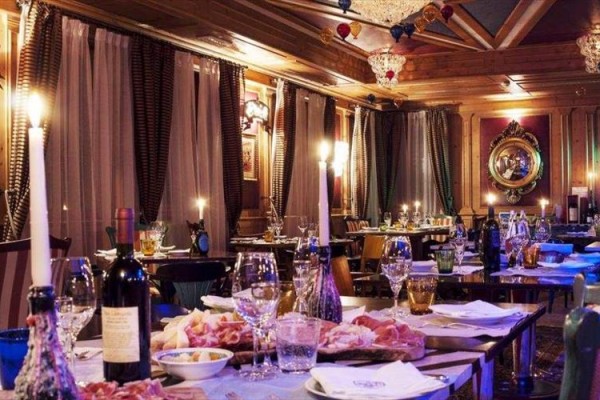 Luksusowa restauracja z nakrytymi stołami i przyciemnionym oświetleniem.