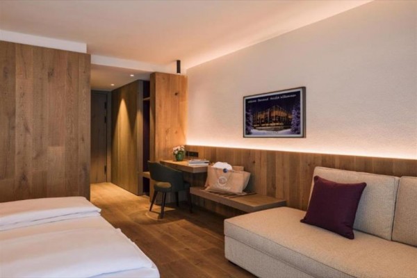 Nowoczesny pokój hotelowy z drewnianą boazerią, biurkiem i sofą.