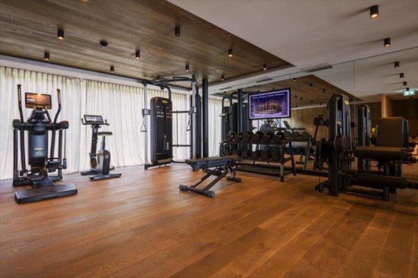 Nowoczesne centrum fitness z różnorodnym sprzętem do ćwiczeń na drewnianej podłodze.