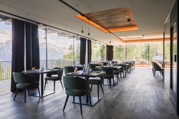 Nowoczesna restauracja z dużymi oknami i widokiem na góry.