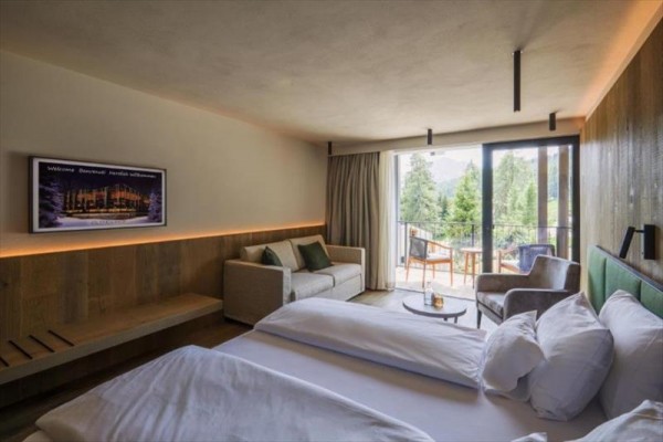 Nowoczesny pokój hotelowy z łóżkiem i balkonem z widokiem na las.