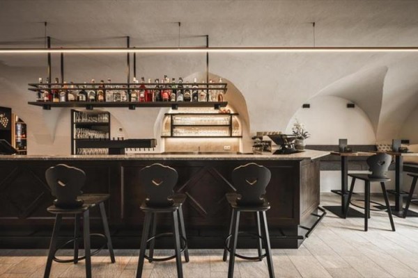 Stylowy bar z wysokimi stołkami i półkami z butelkami alkoholu.