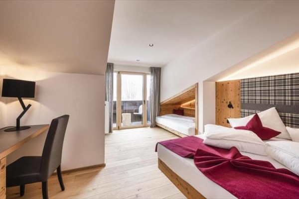 Nowoczesny pokój hotelowy z podwójnym łóżkiem, biurkiem i balkonem.