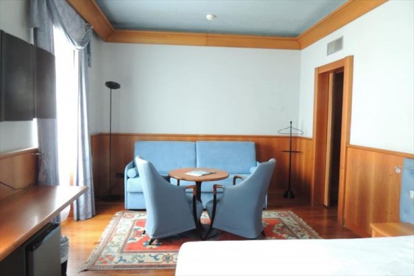 Pokój hotelowy z niebieską kanapą, okrągłym stołem i dwoma fotelami.