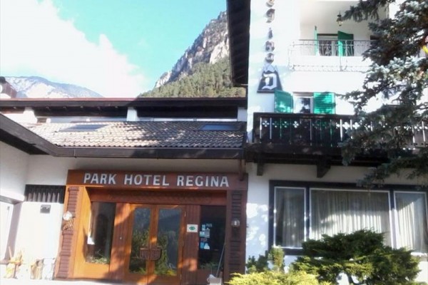 Wejście do Park Hotel Regina z górami w tle.
