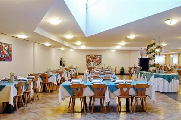 Elegancka restauracja z okrągłymi stołami pokrytymi niebieskimi obrusami.