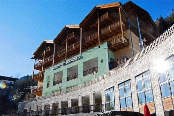 Hotel z tarasami i drewnianymi balkonami pod błękitnym niebem.