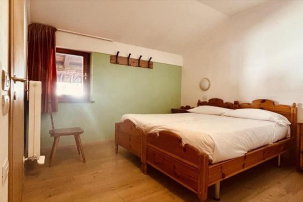 Pokój hotelowy z drewnianym łóżkiem i krzesłem obok okna.