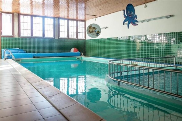 Kryty basen z kolorowymi kafelkami i rysunkiem ośmiornicy na ścianie.