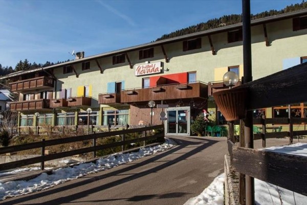 Hotel z drewnianymi balkonami i napisem na fasadzie w górskim regionie.