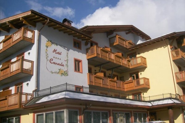 Hotel z drewnianymi balkonami na tle niebieskiego nieba z chmurami.